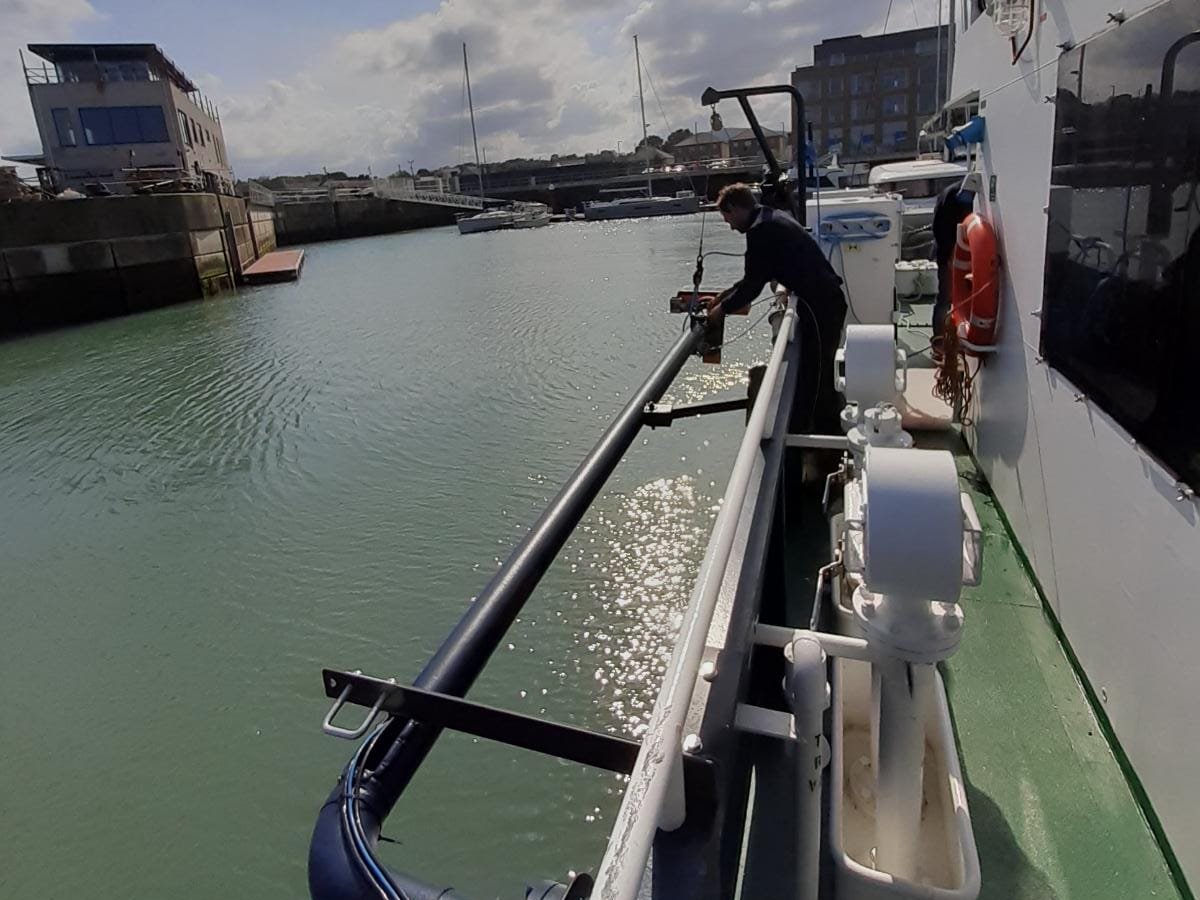 Fitting a sonar pole over the side of a survey boat, alongside in a harbour