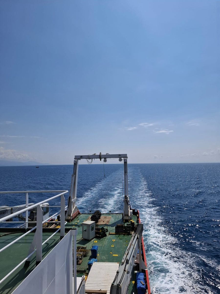 Aft deck of a survey vessel with its A-frame and winch, wake behind