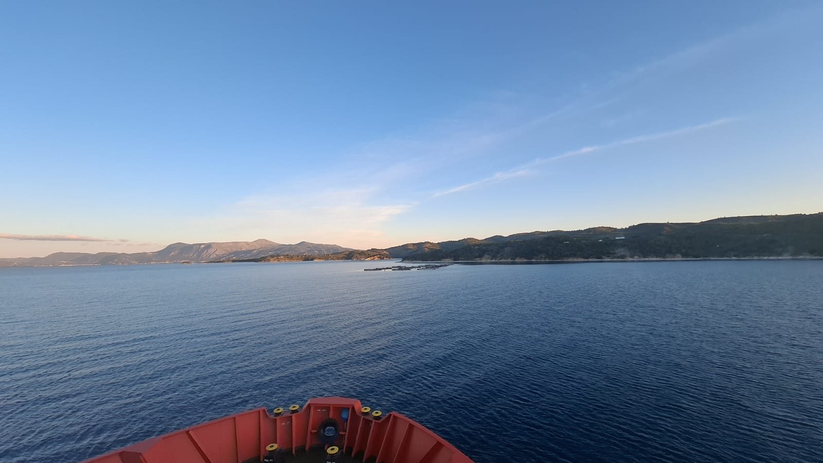 The bow of a survey vessel at dawn, heading for a coastline