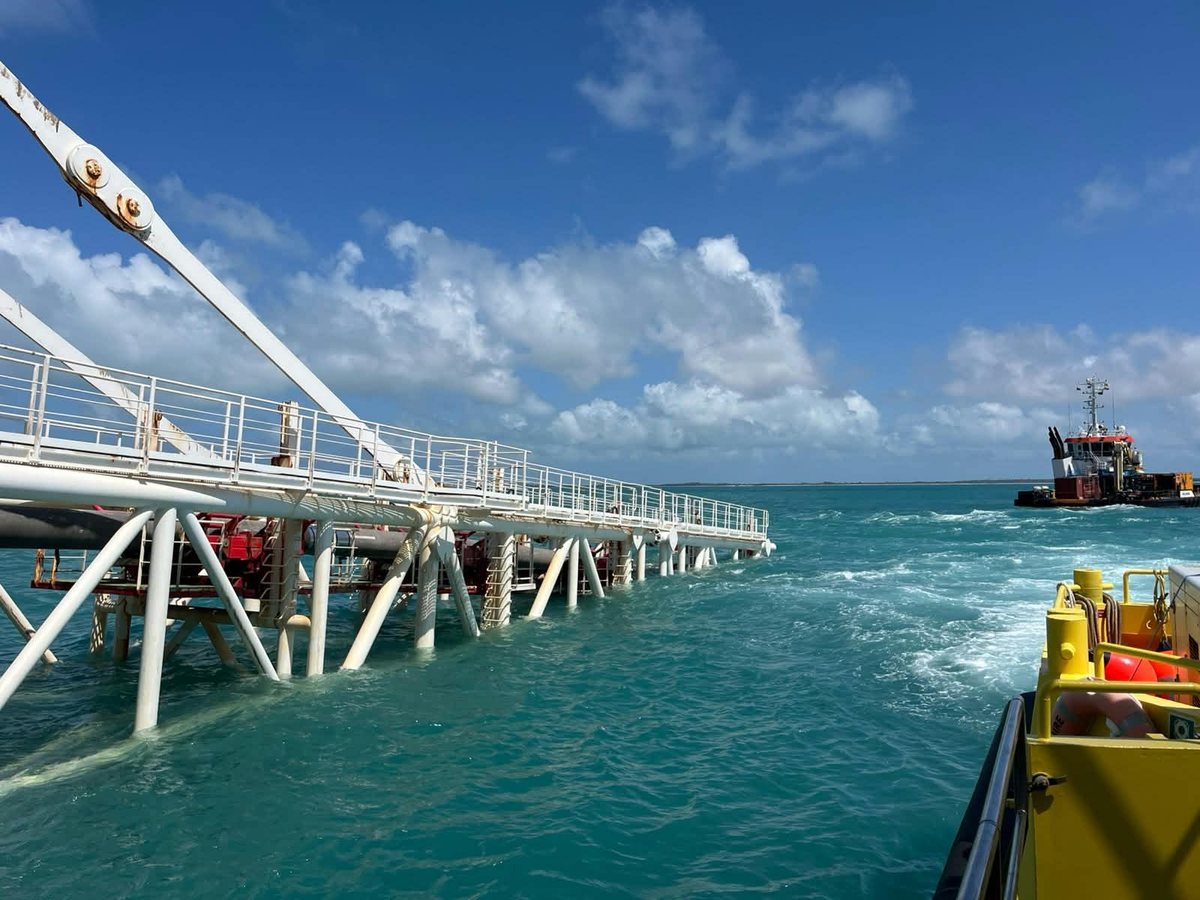 A pipe trestle running out to sea, a tug alongside