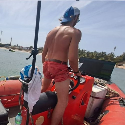 Dylan Roux at the helm of a survey boat, in shallow water